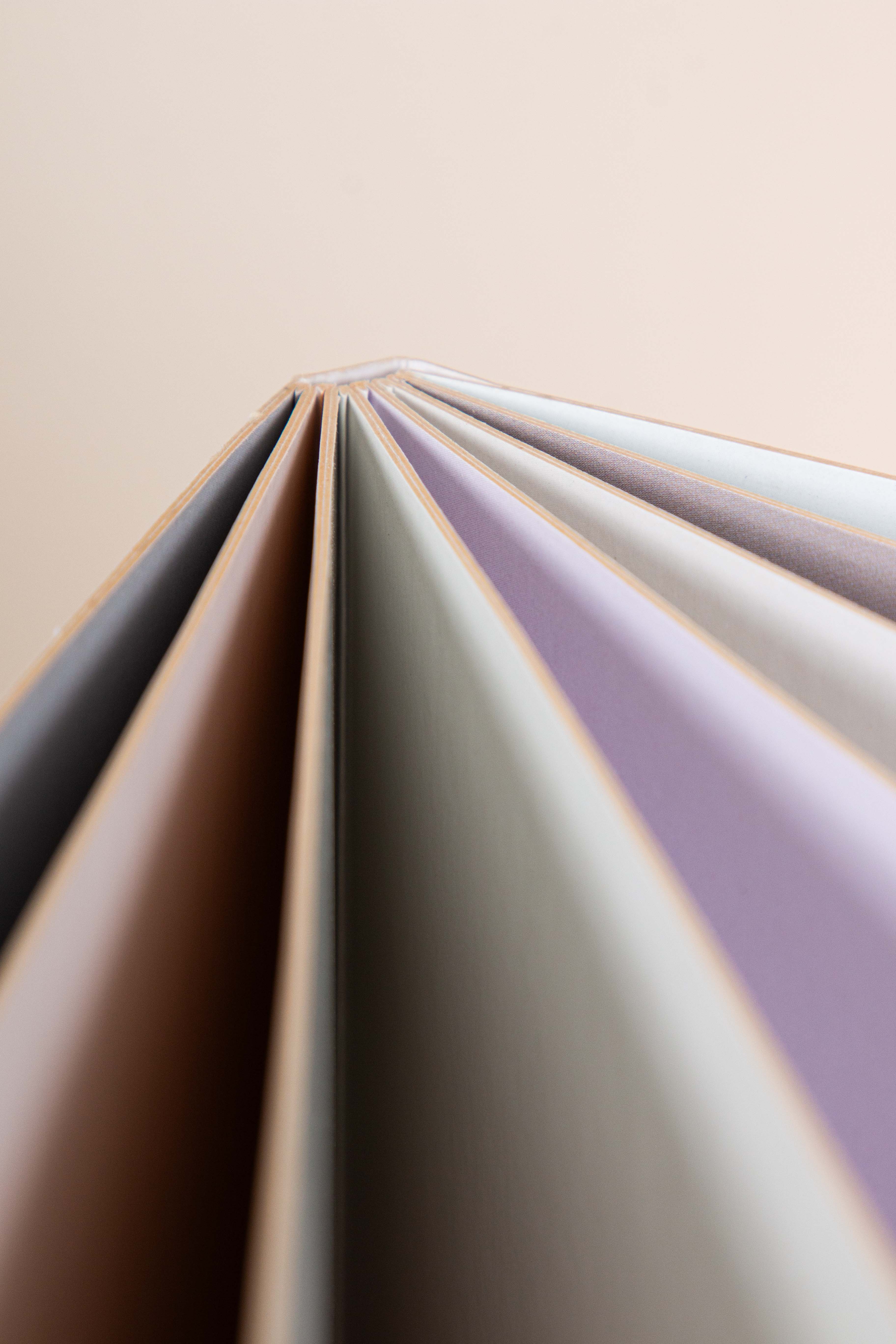 Close-up of several open book pages with different pastel colors.
