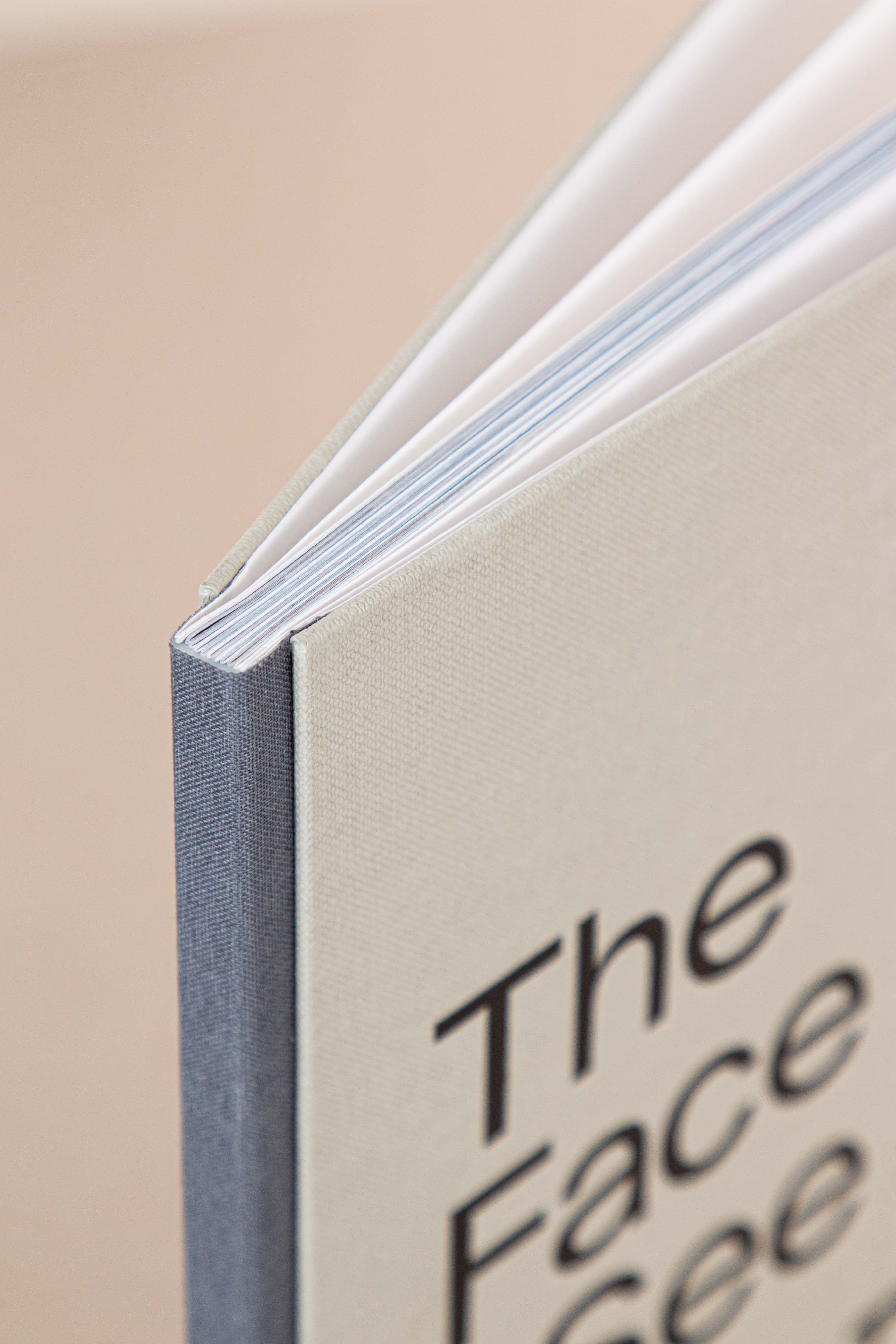 Close-up of a hardcover book with a beige cover and partial text reading The Face.